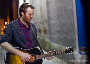 John Mark McMillan plays an acoustic guitar in an alley in Macon, Georgia