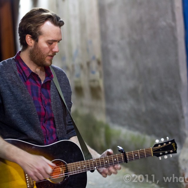 John Mark McMillan plays an acoustic guitar in an alley in Macon, Georgia